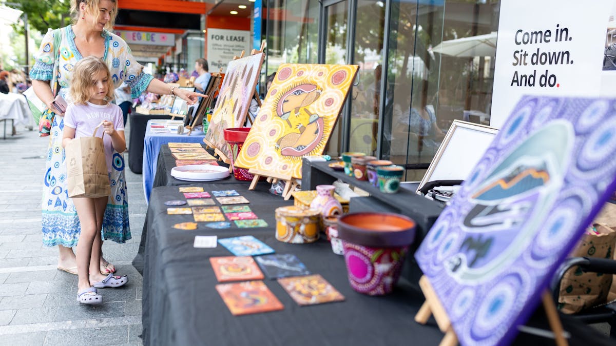 A market‑goer browsing unique First Nations artworks from local makers