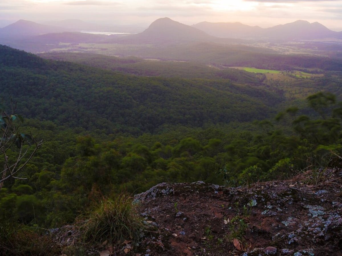A view over a green valley with a mountain range behind A view over a green valley with a mountain range behind