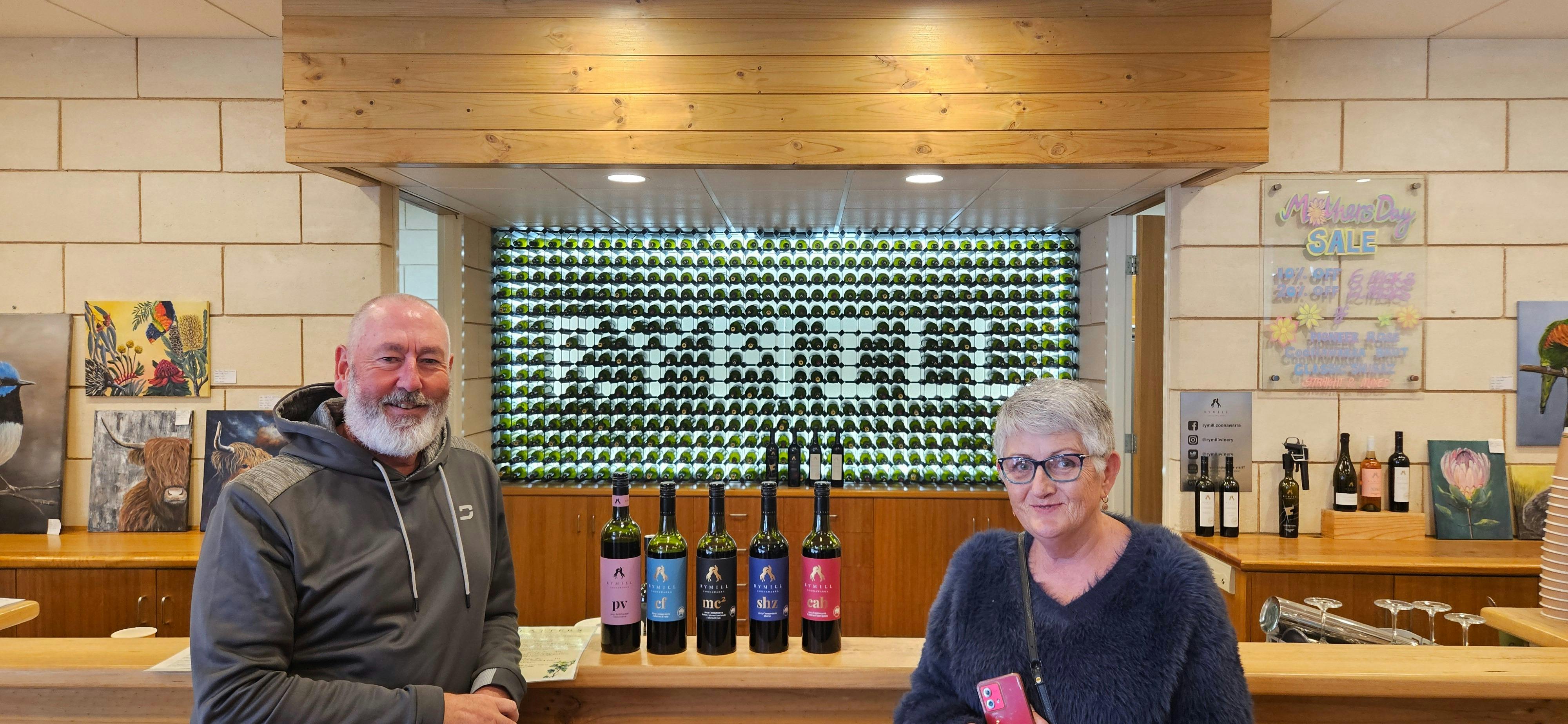 Coonawarra Experiences guests at cellar door with wine display behind.