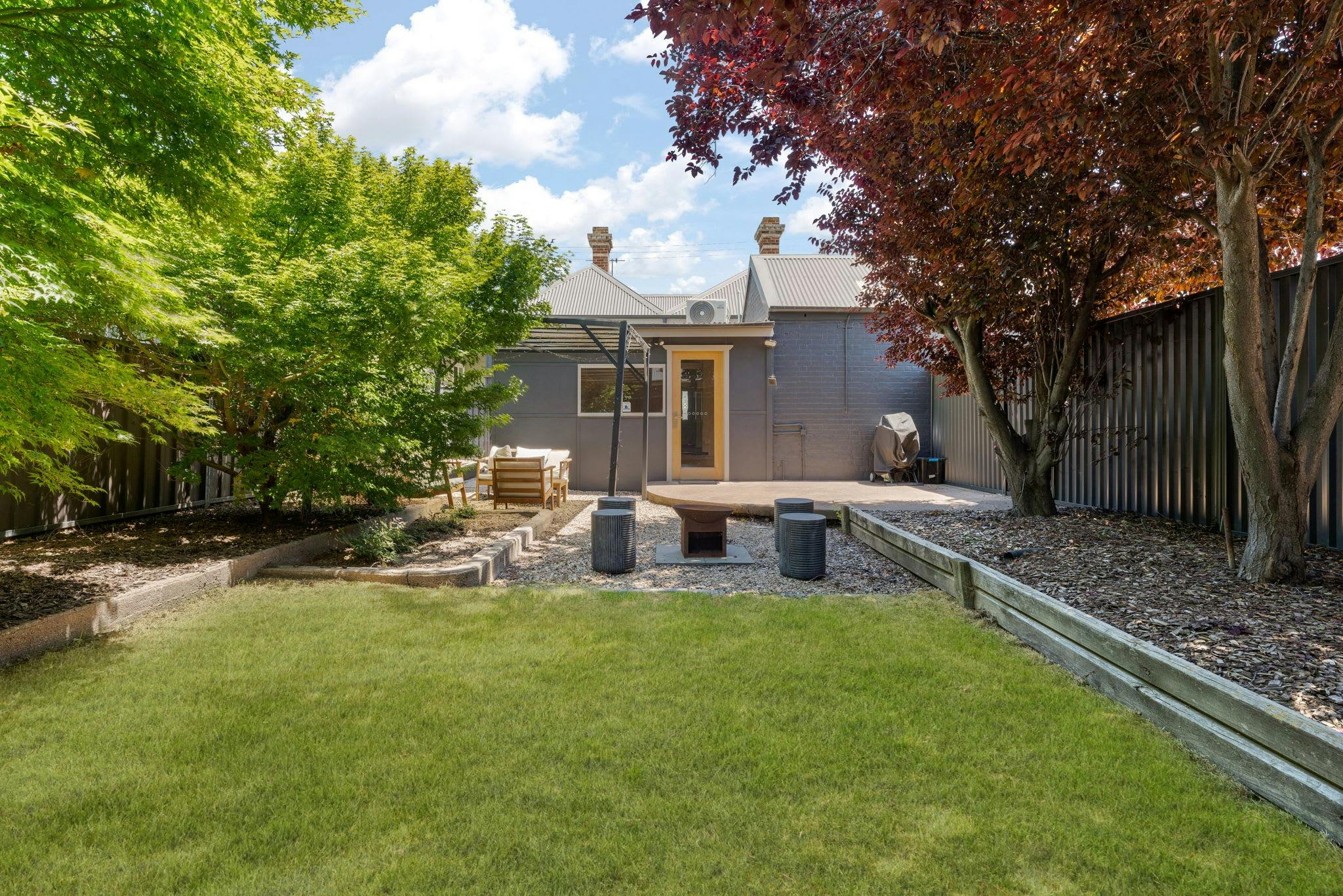 Large spacious backyard with lawn, awning and outdoor seating, fire pit