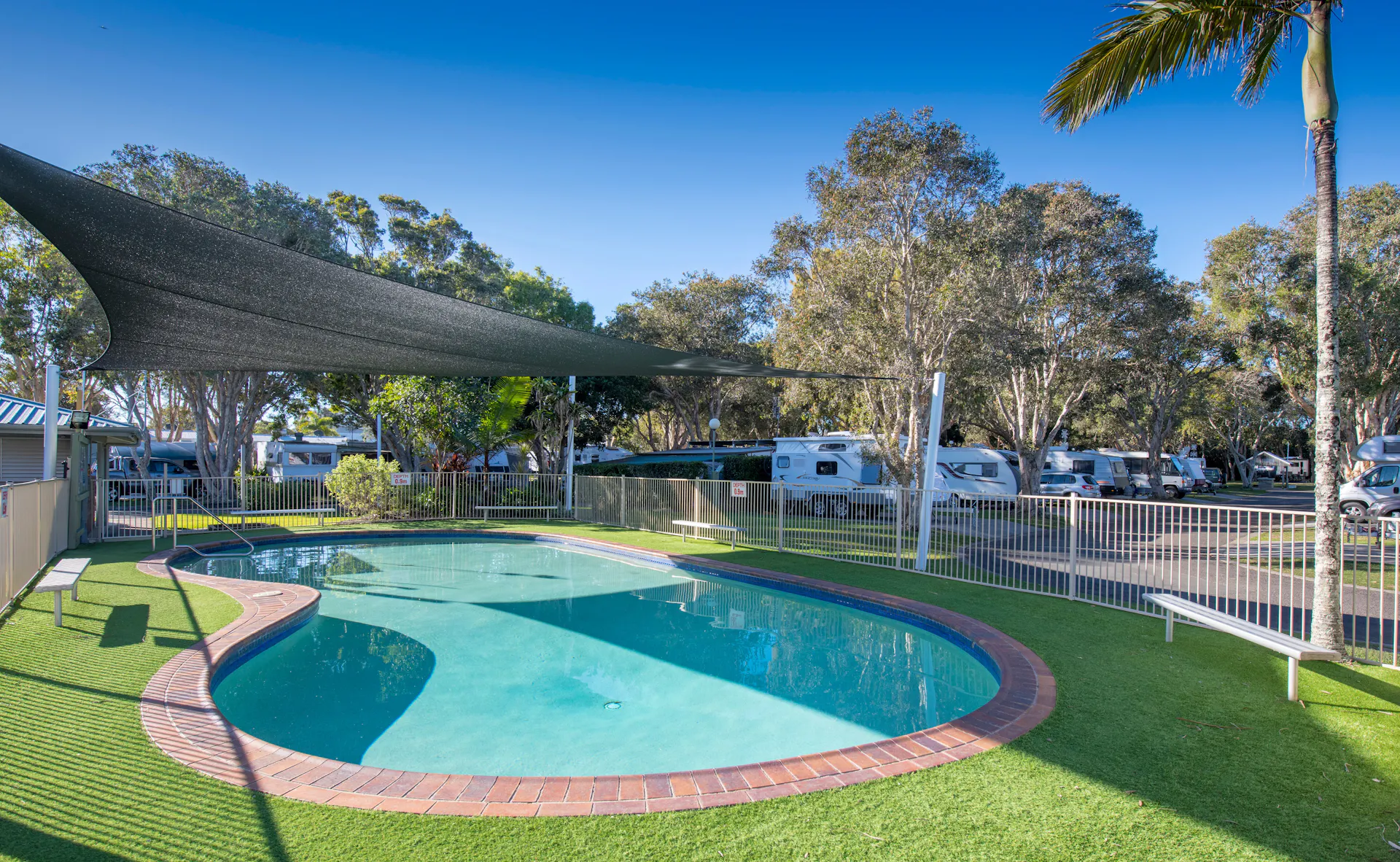 Shot of Mudjimba Beach Holiday Park swimming pool with no one swimming. Surrounded by trees and sun