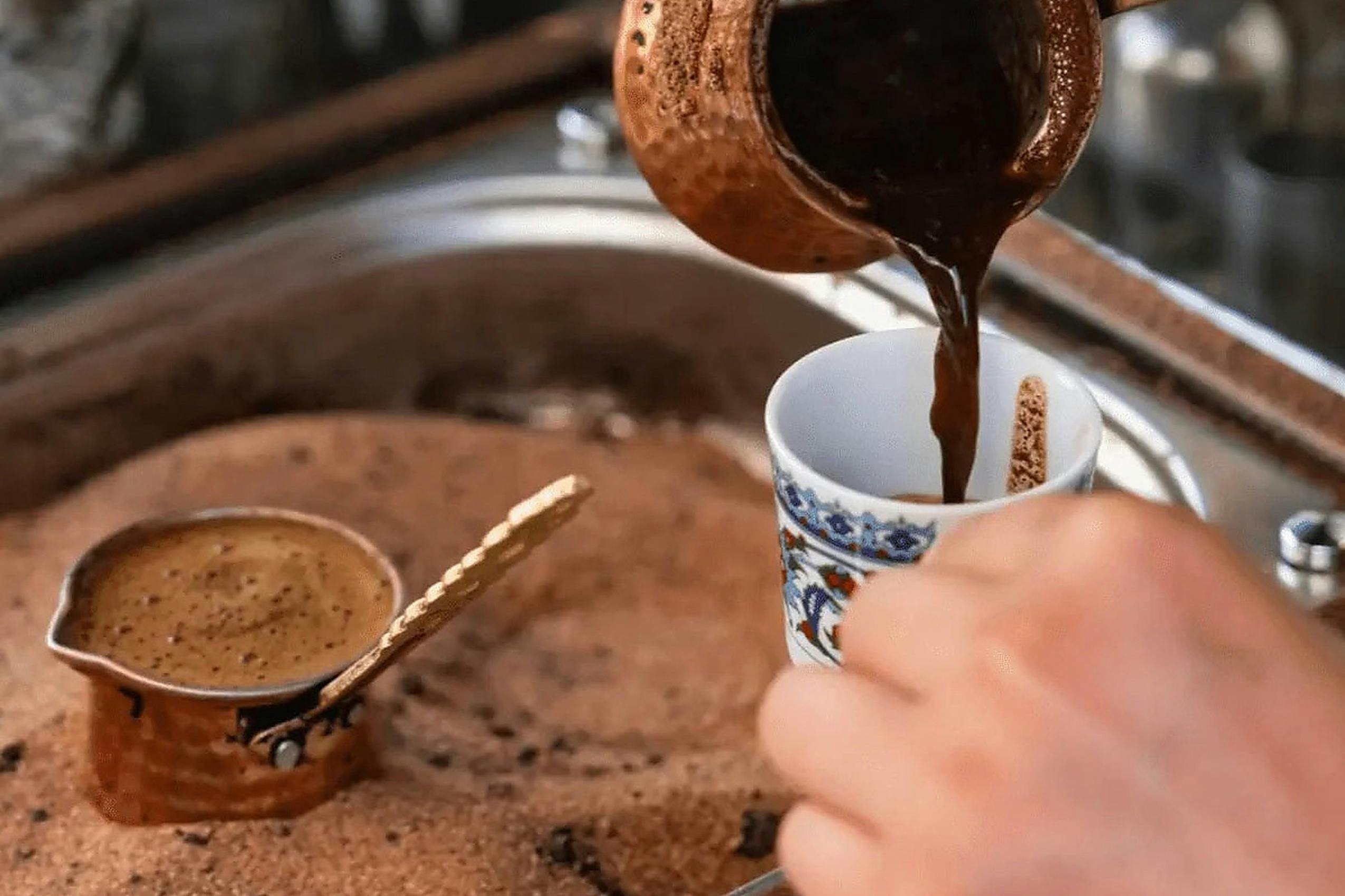 Host pouring freshly brewed Turkish coffee into a cup