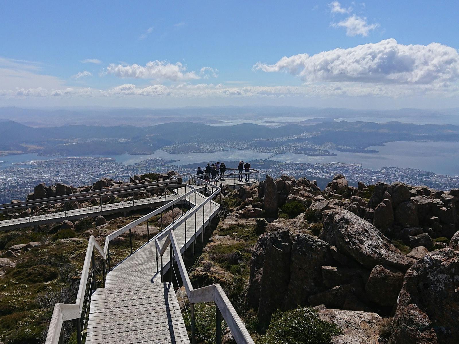 A small group of people enjoying the view over Hobart from a lookout  on kunanyi/Mt Wellington.