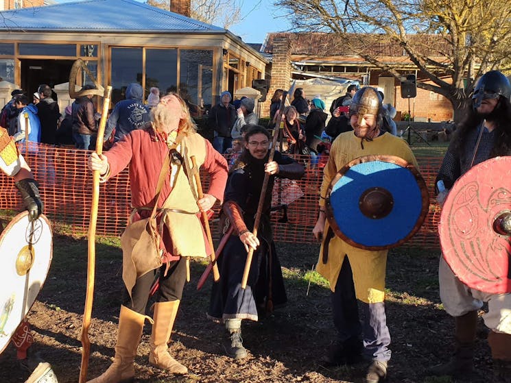 Six men in Viking battle costume line up for the camera; one slightly behind the others