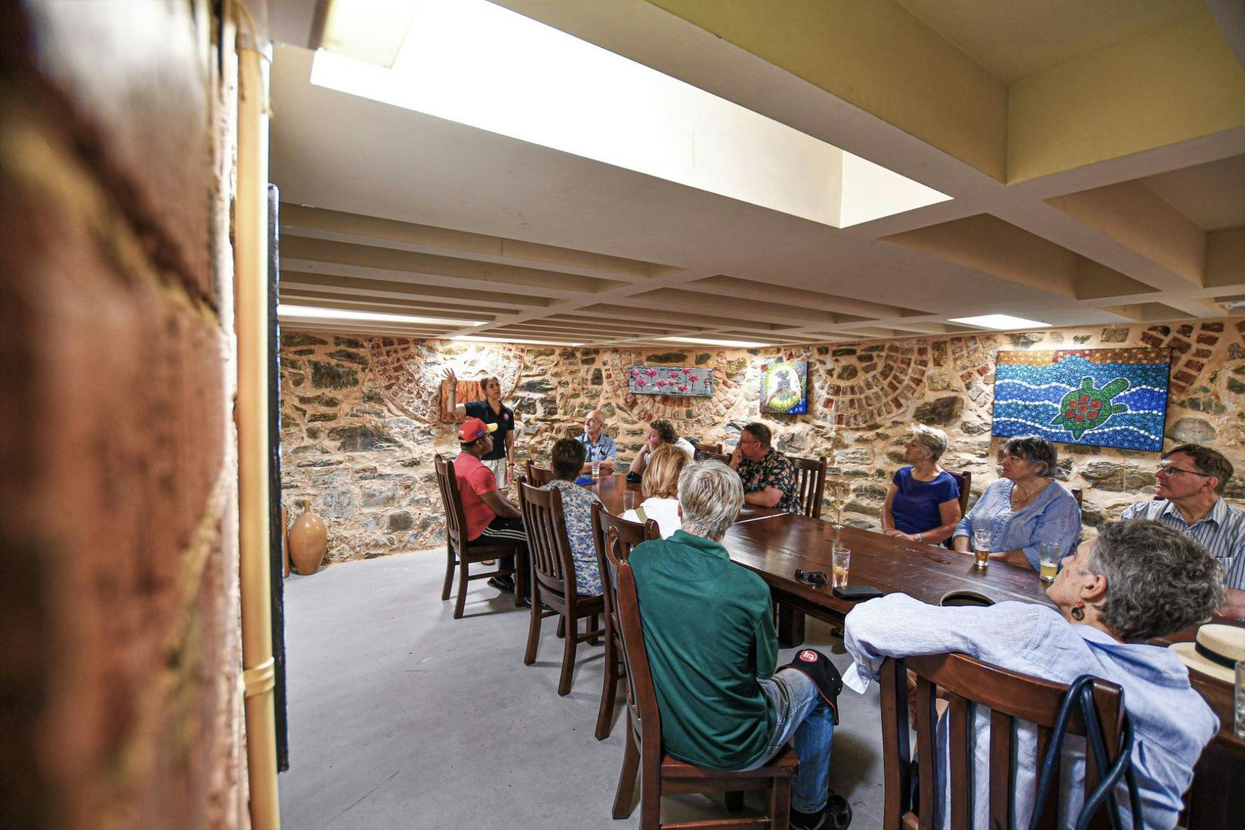 A tour group sits in a pub cellar listening to their tour guide.
