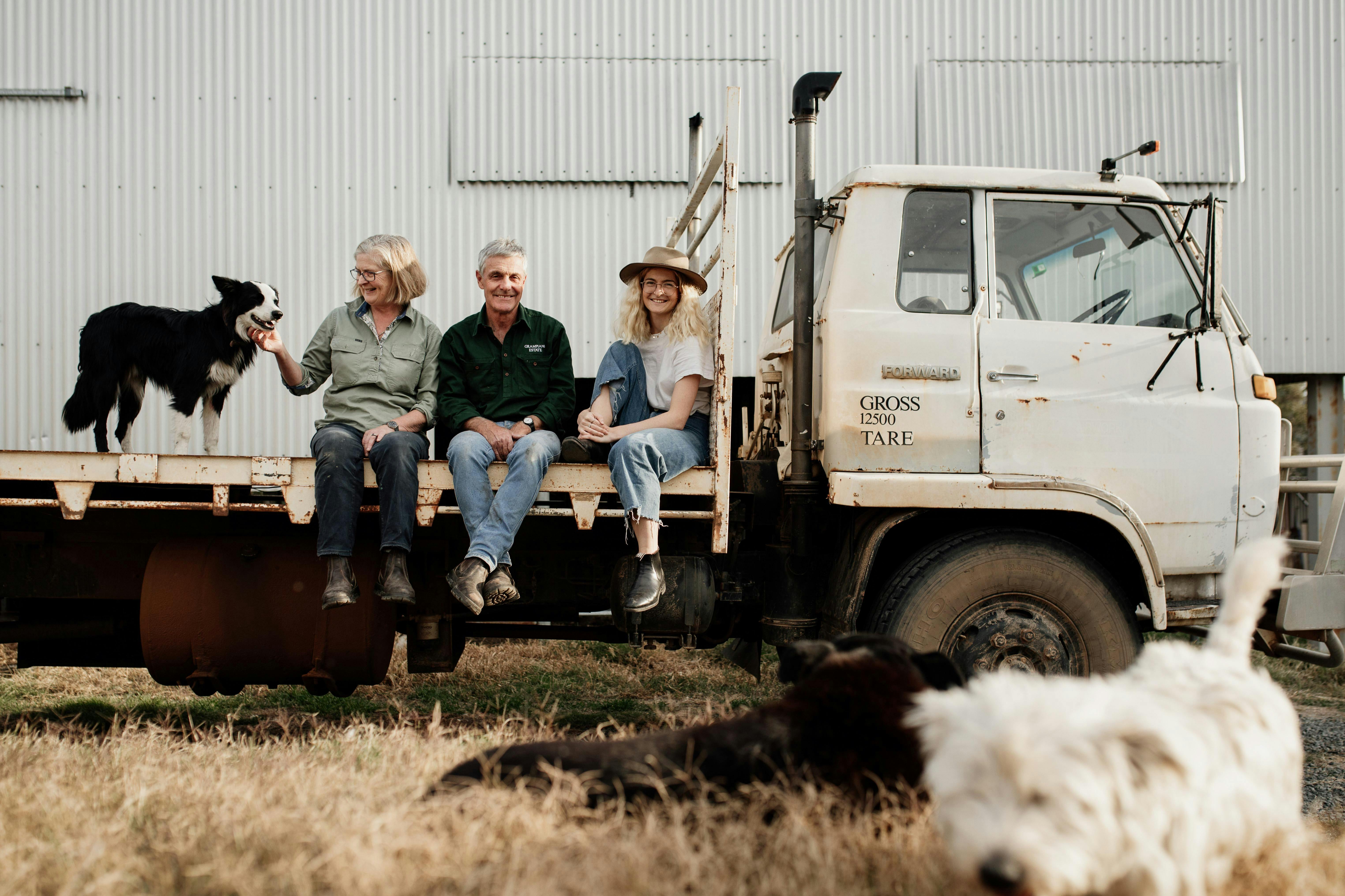 Tom, Sarah and Polly Guthrie from Grampians Estate sitting on the back of a truck with their dogs