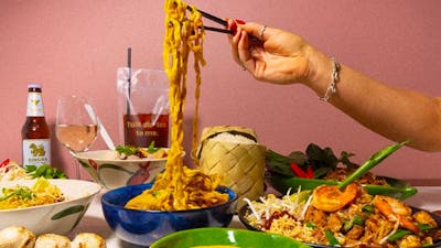 Hand using chopsticks to pick up noodles