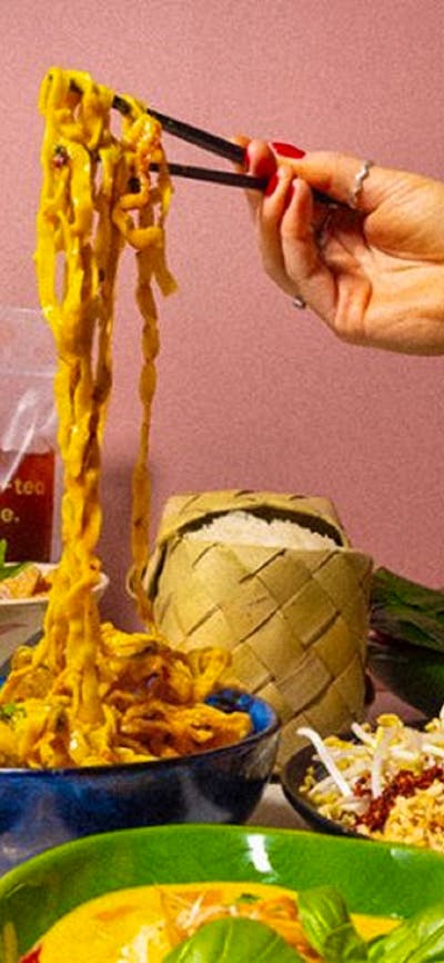 Hand using chopsticks to pick up noodles
