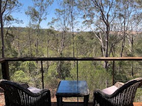 outdoor lounge on deck surrounded by gum trees with blue sky
