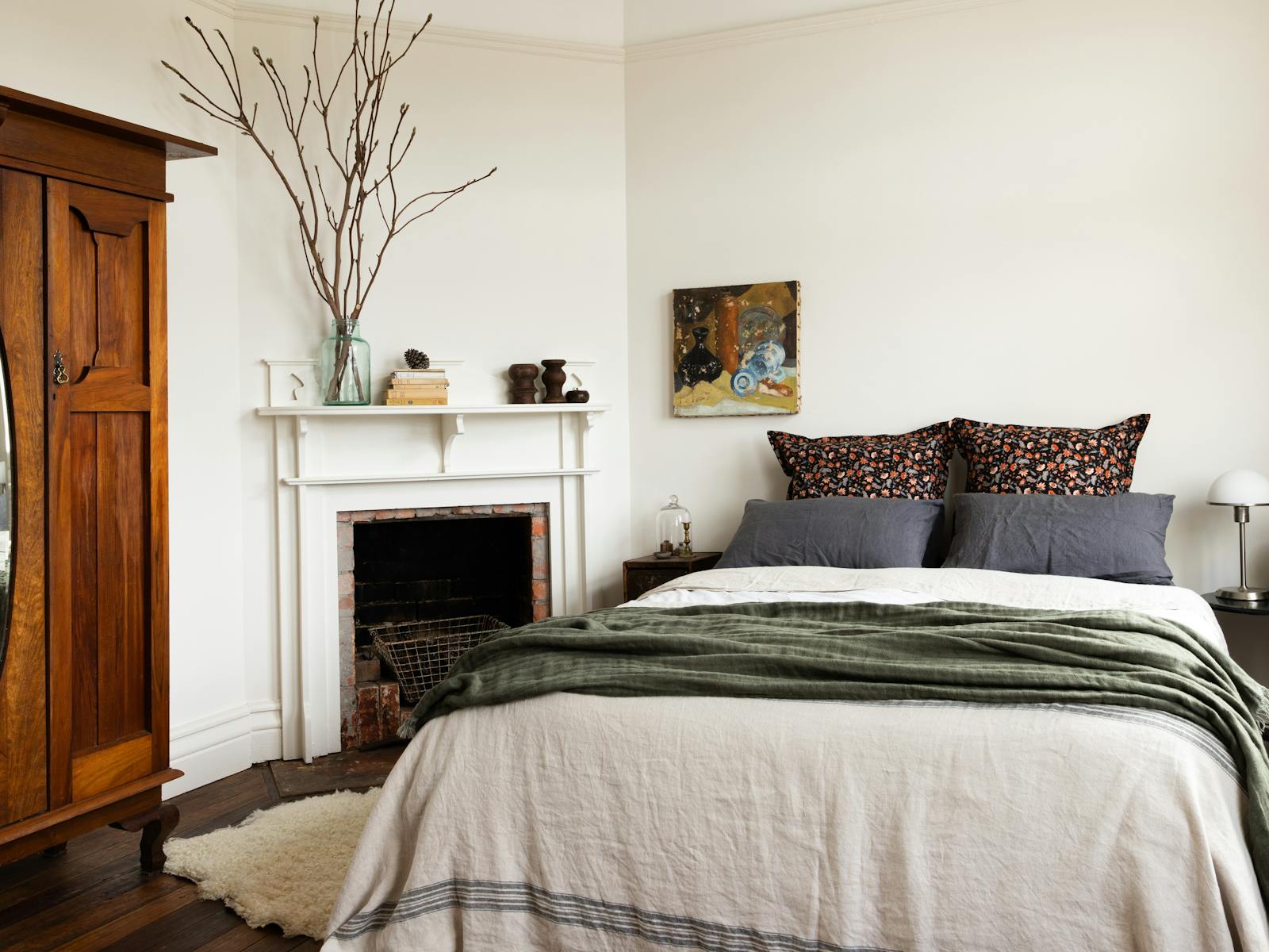 A bedroom with queen bed, textured linens and vintage artwork