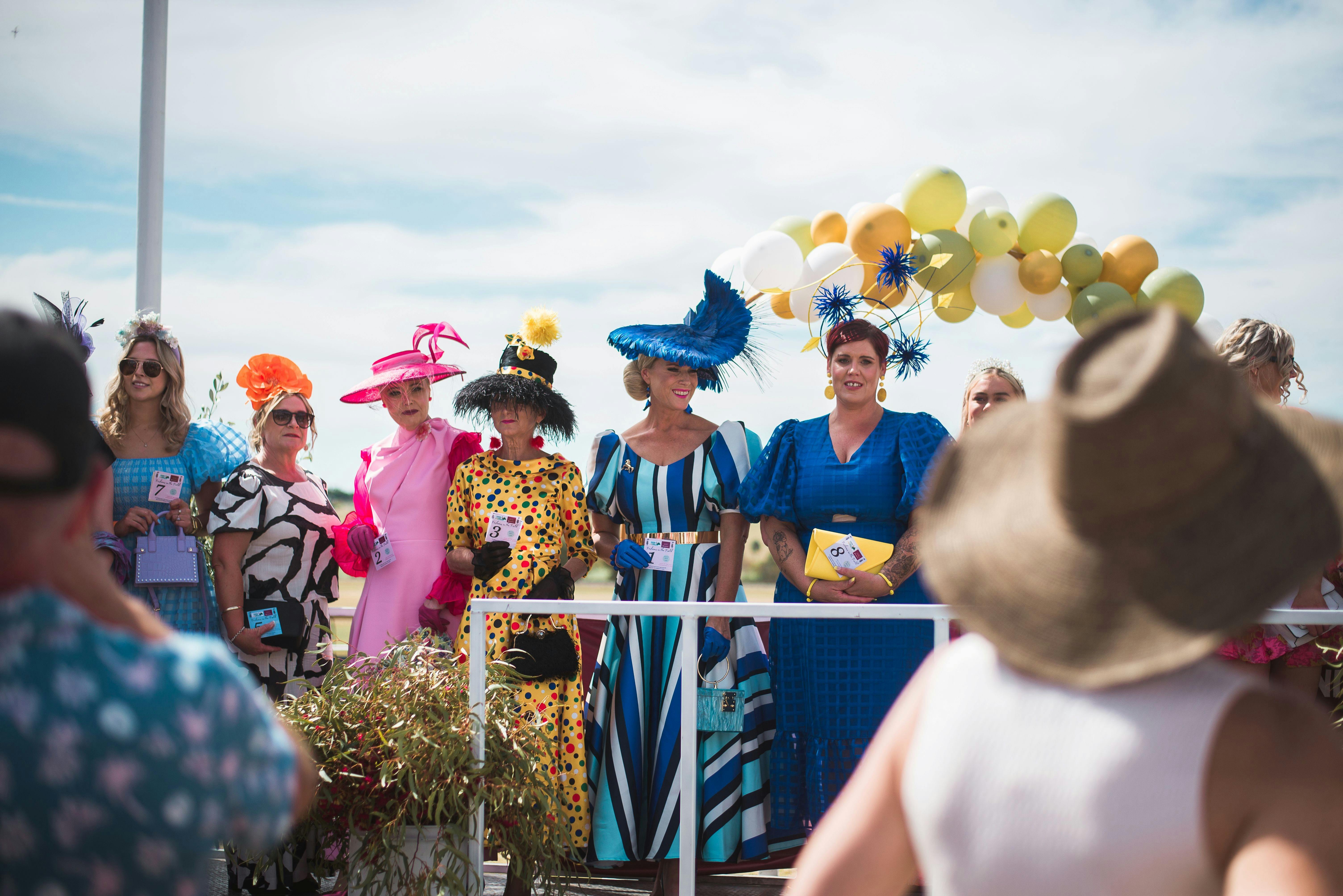 Mens' Fashions on the Field - a yellow balloon arch behind them with a beautiful blue sky.