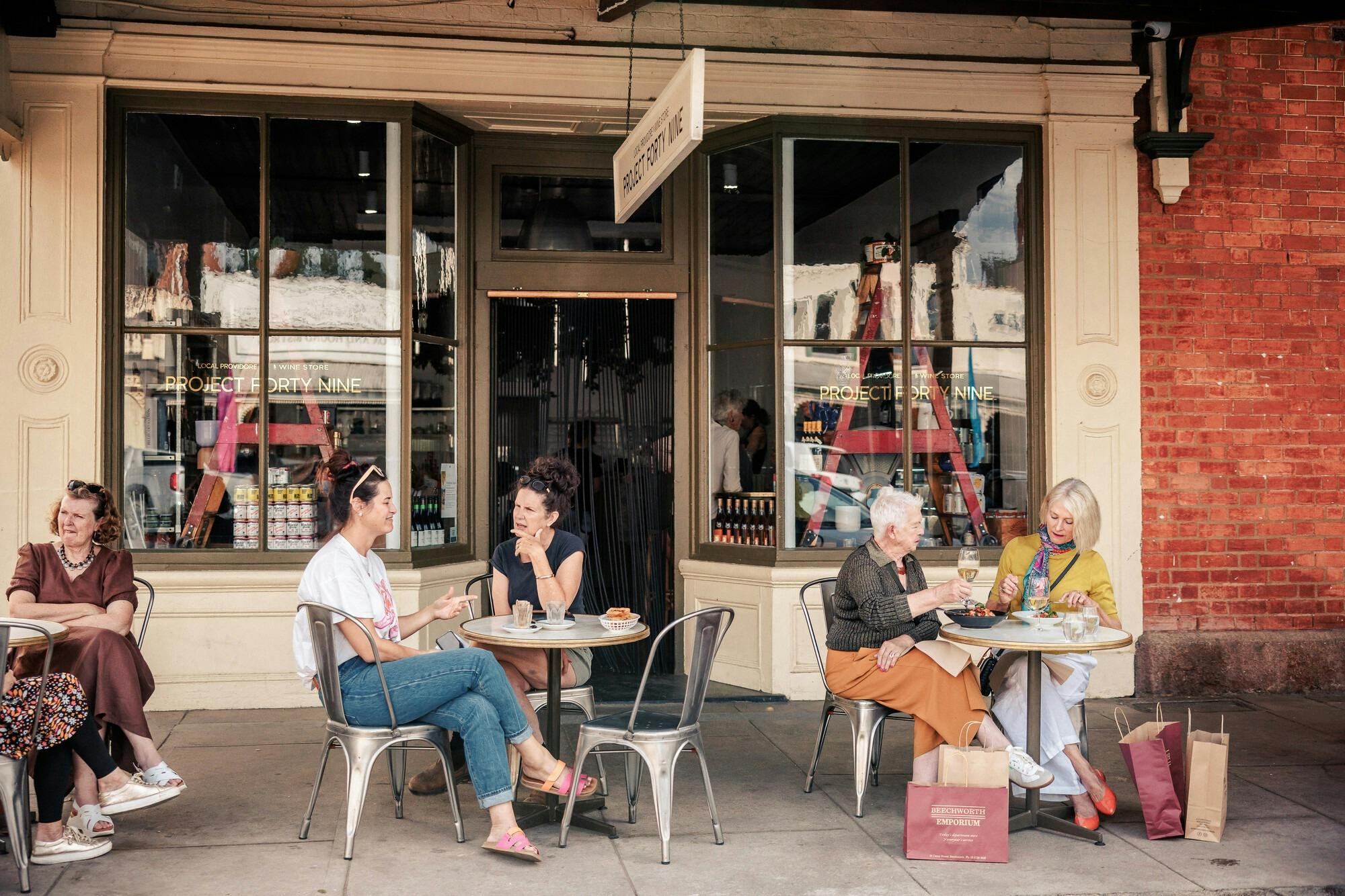 Several tables of people having coffee outside a charming cafe in a heritage building