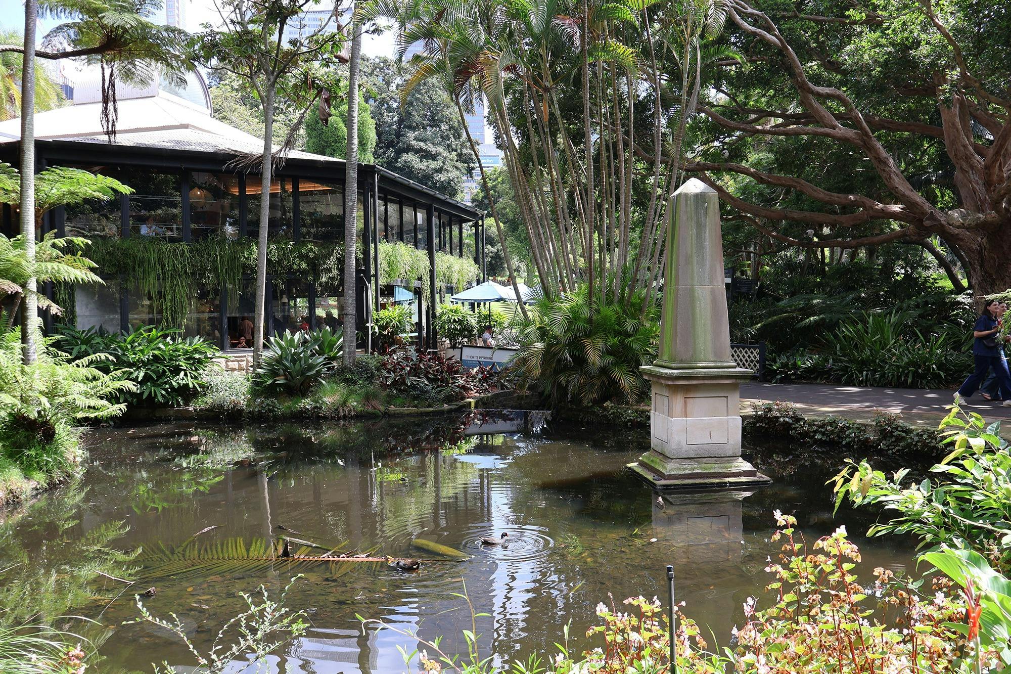 A pond with an obelisk statue erected and a restaurant in the background