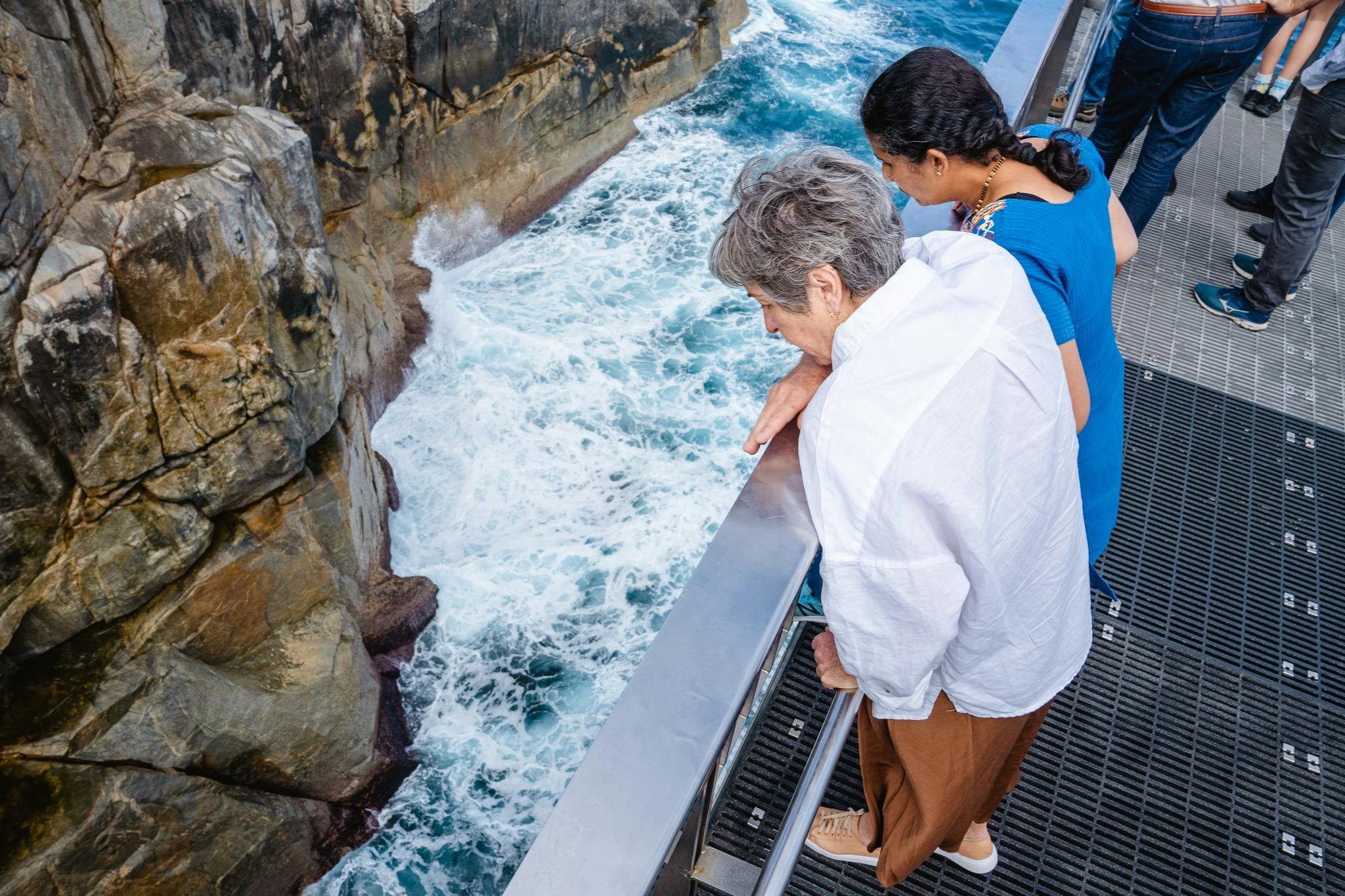 two women looking over a rail into granite chasm and waves