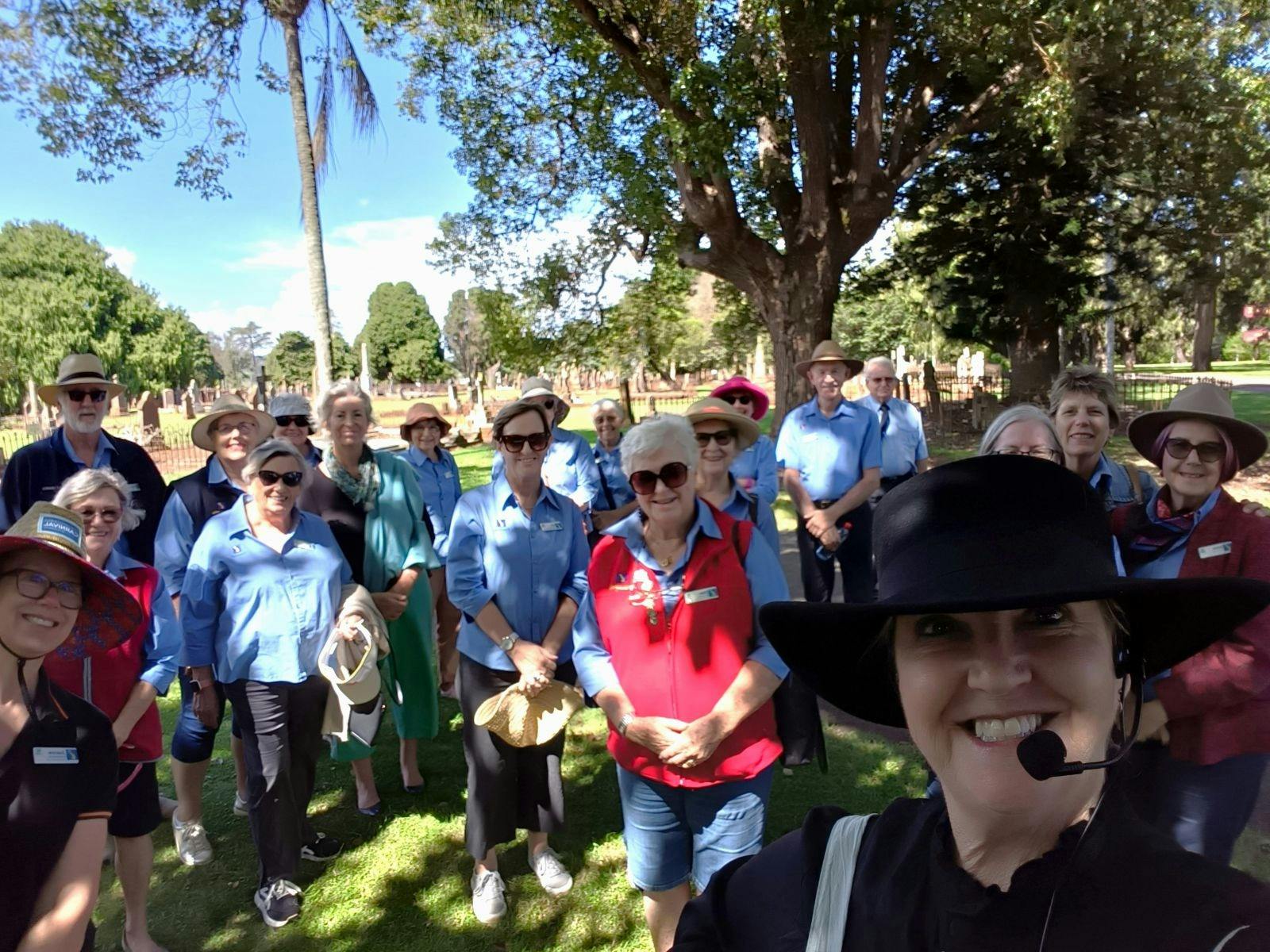 A tour group smiles at the camera in the cemetery, a selfie taken by guide lisa in the foreground