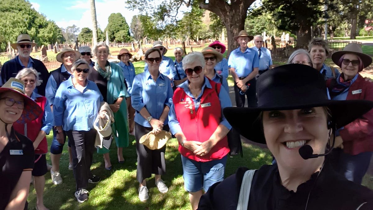A tour group smiles at the camera in the cemetery, a selfie taken by guide lisa in the foreground