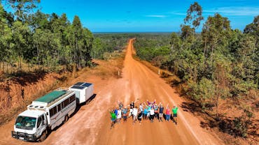 group jumping on dirt road next to truck