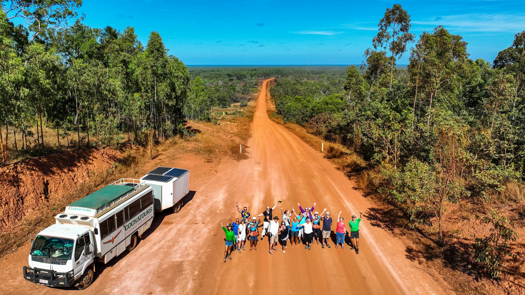 group jumping on dirt road next to truck group jumping on dirt road next to truck