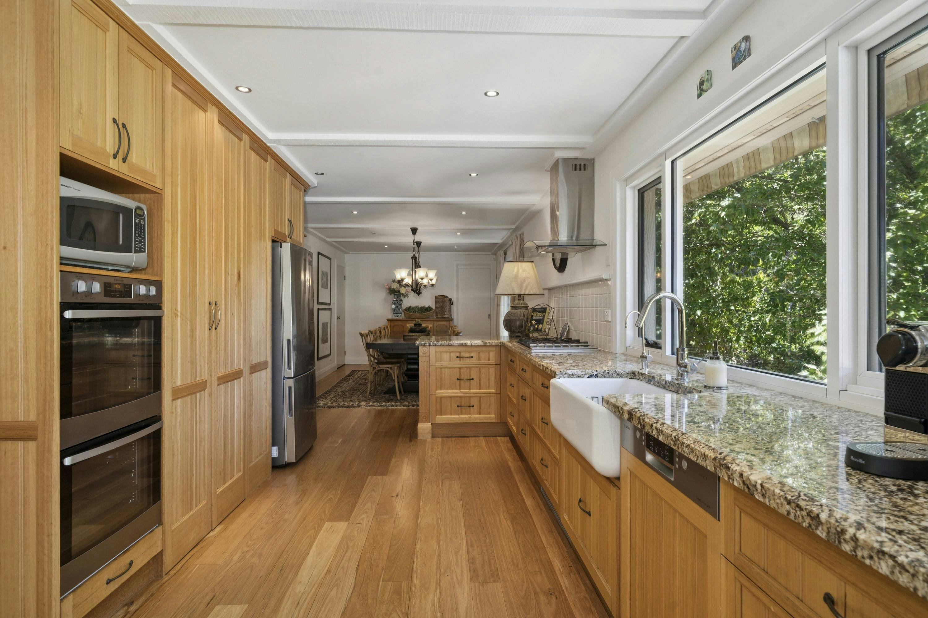 Kitchen with timber cabinetry, double wall ovens and a farmhouse sink