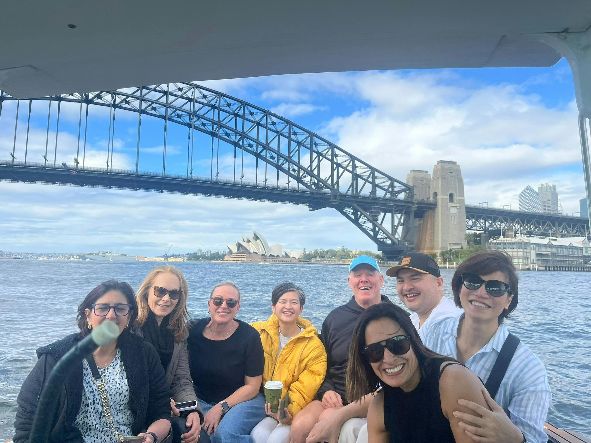以海港大桥和歌剧院为背景的船上微笑的人们
