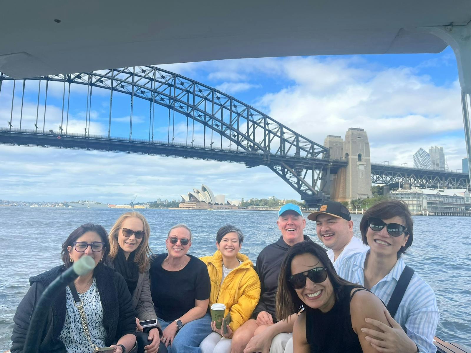 Smiling people on a boat with the Harbour Bridge & Opera House background