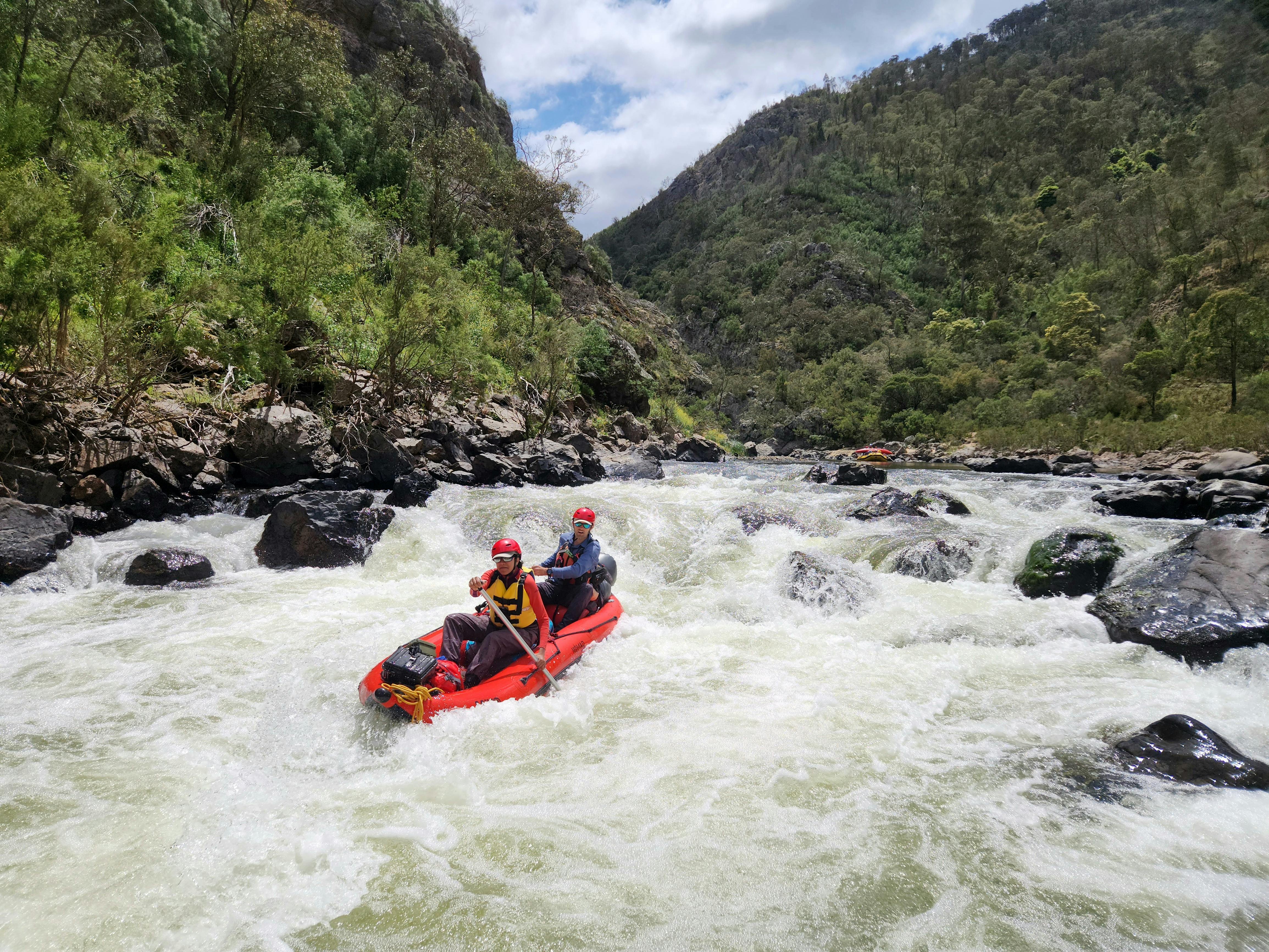 A man and a woman in a 2 person inflatable boat going down 'Compressor Rapid' on the Snowy River.