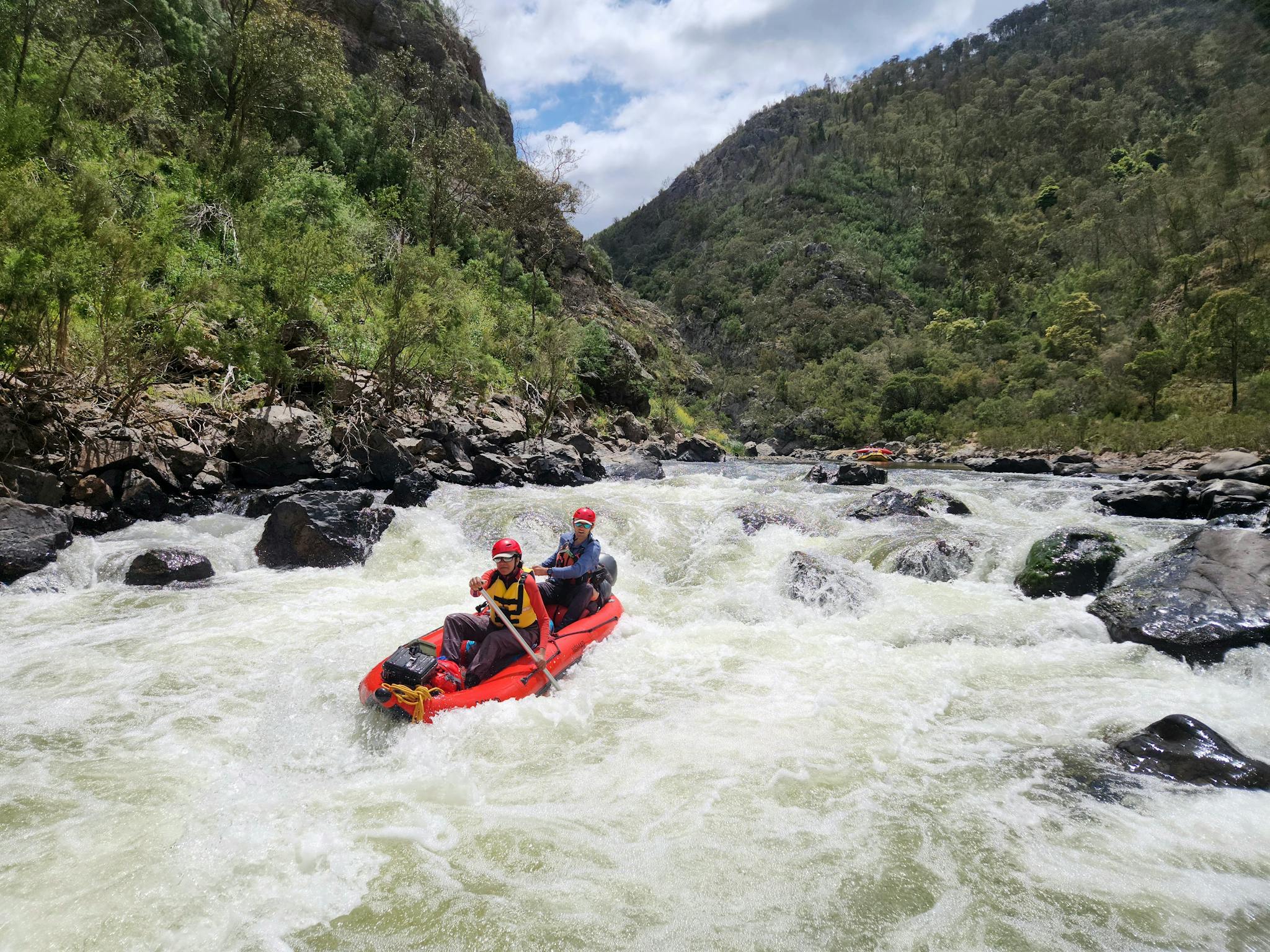 A man and a woman in a 2 person inflatable boat going down 'Compressor Rapid' on the Snowy River.