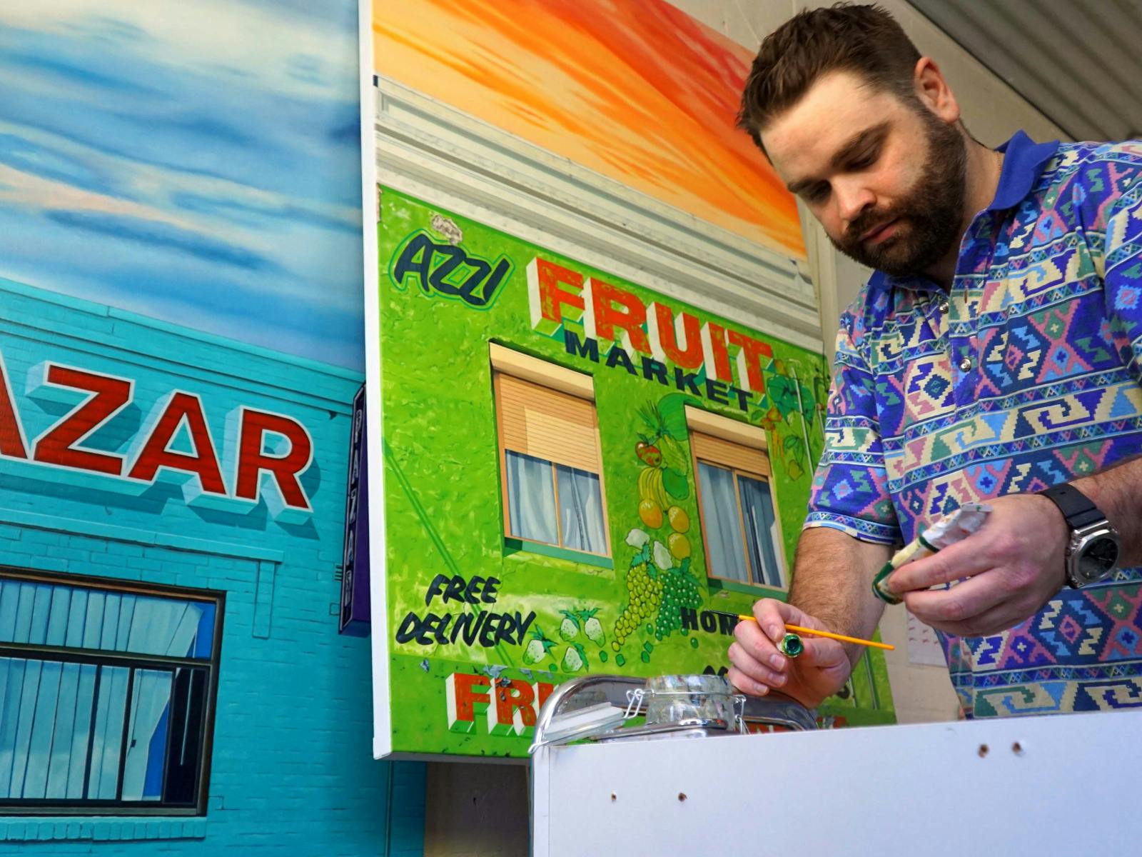 Donovan Christie working on a bright fruit market painting in his studio.