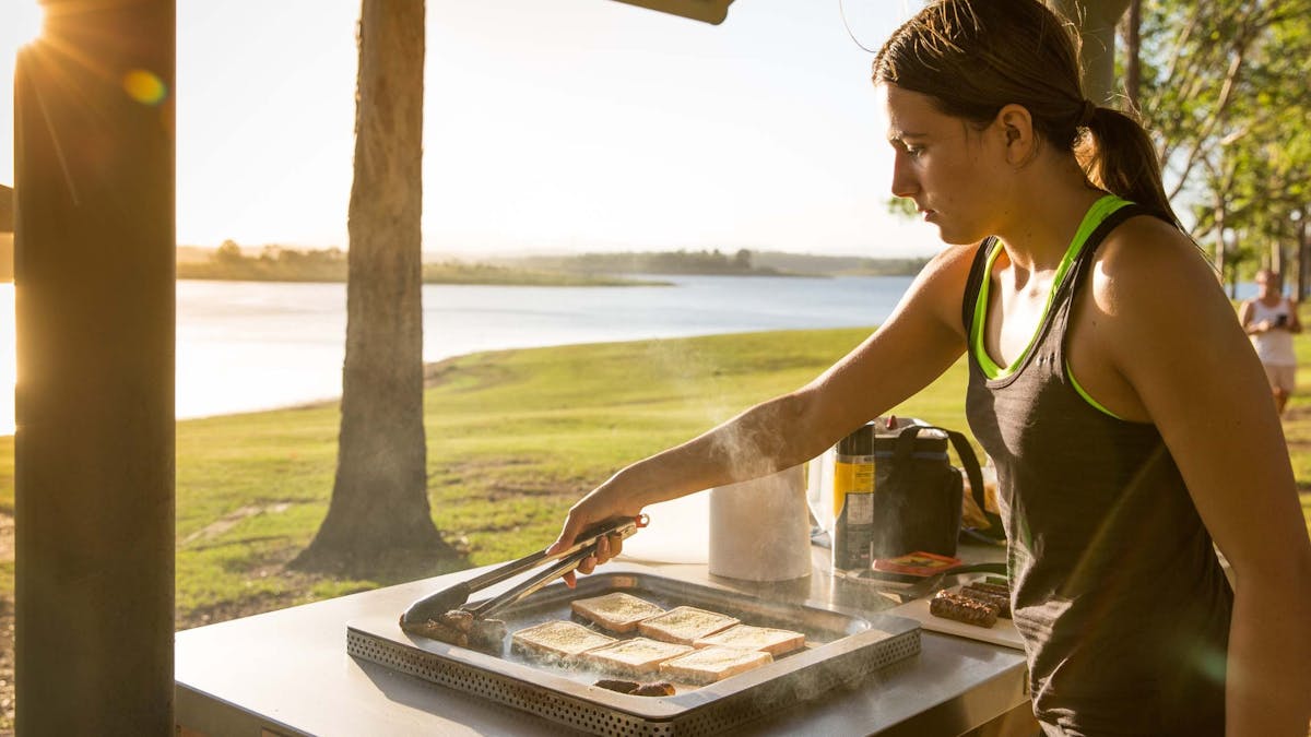 A woman cooking   with views of Lake Samsonvale, Bullocky Rest