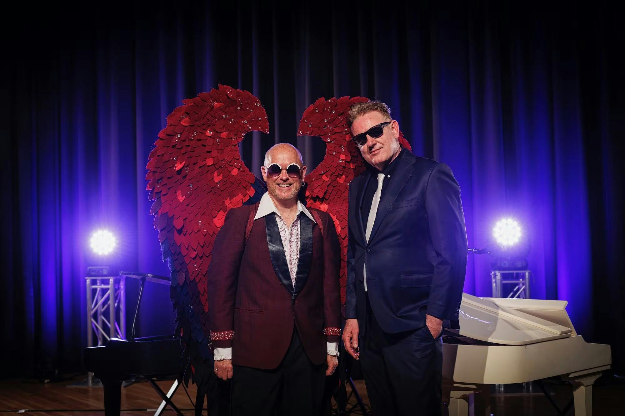 Two men standing in front of a piano