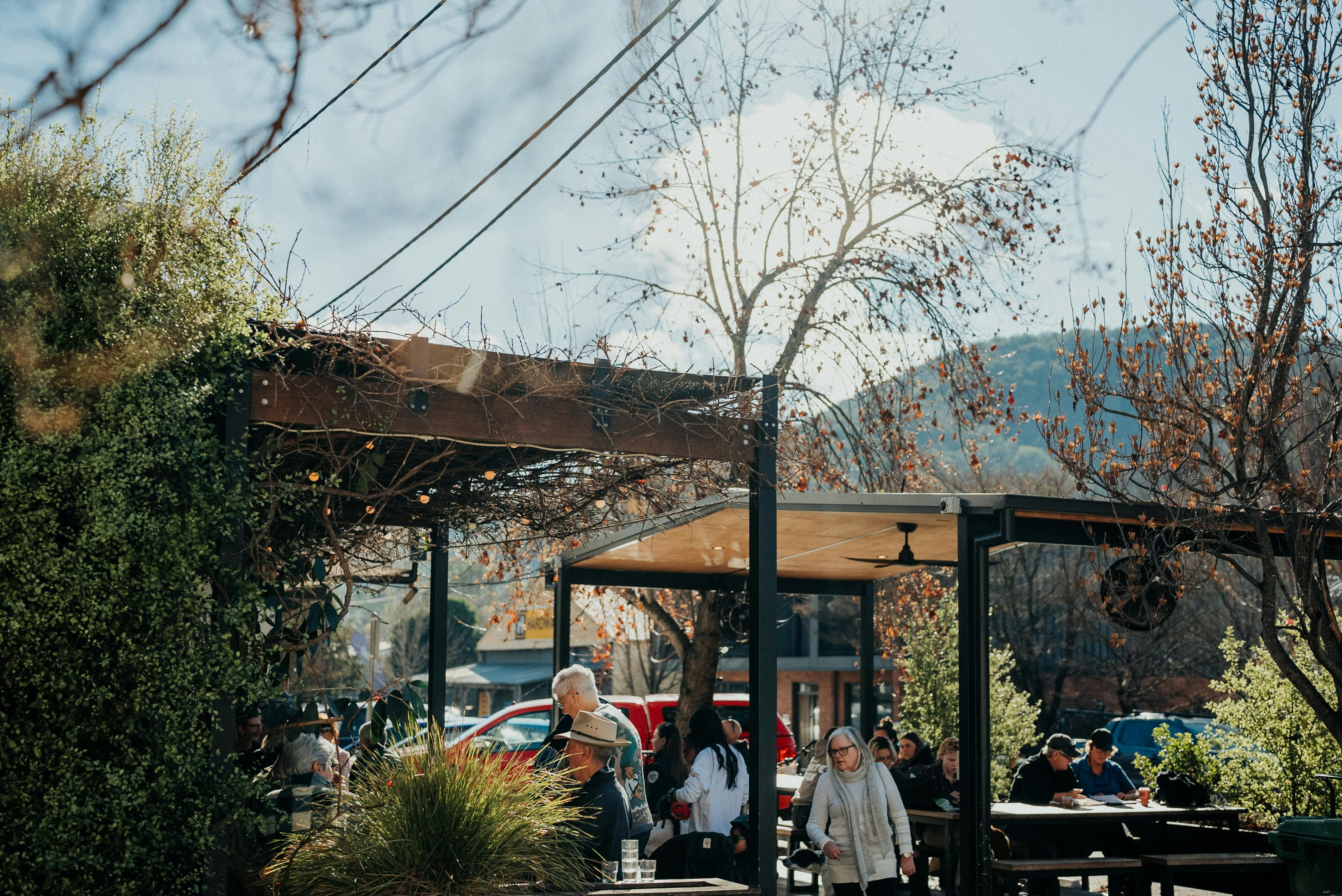 People sitting enjoying coffee in undercover outdoor area on sunny day