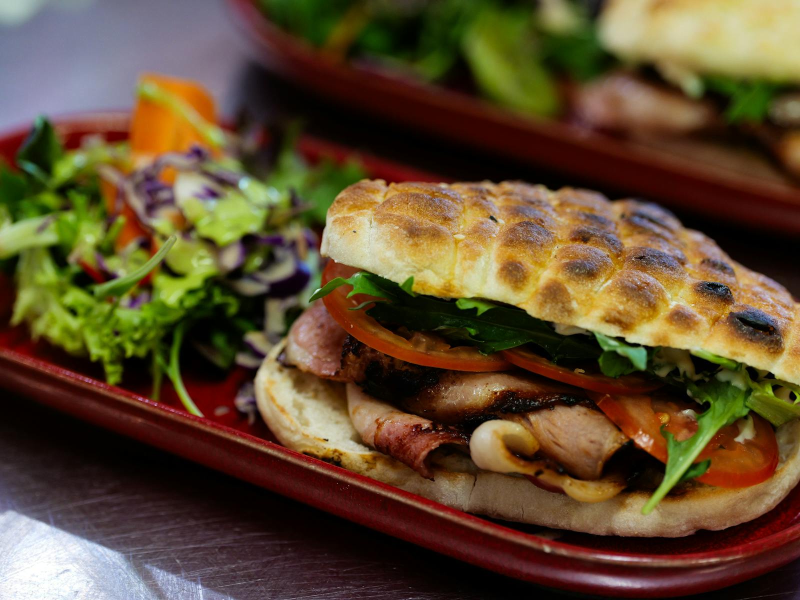 A oblong plate with small salad and BLT