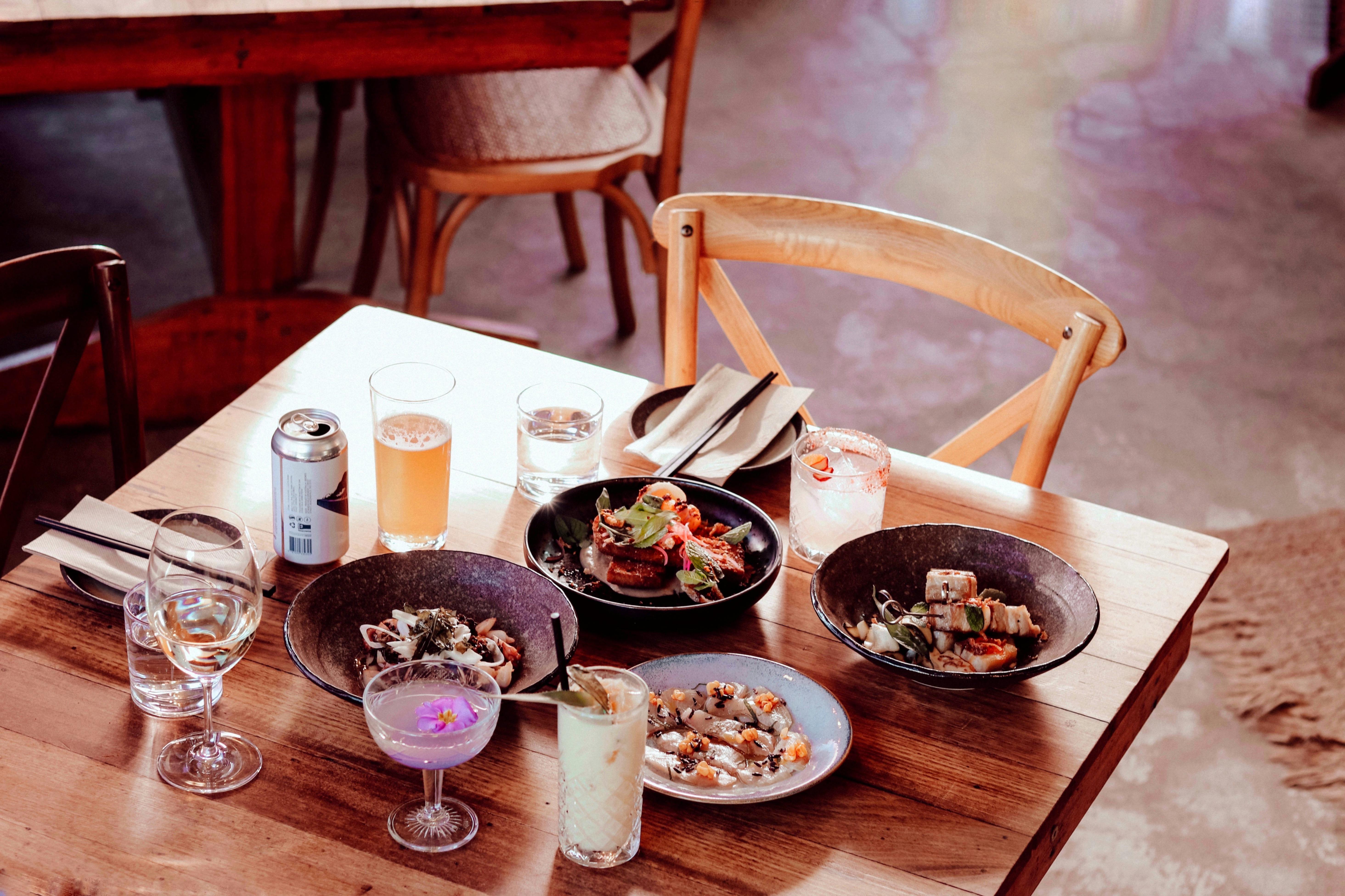 A tablescape features an array of savoury dishes,  cocktails, beer and water