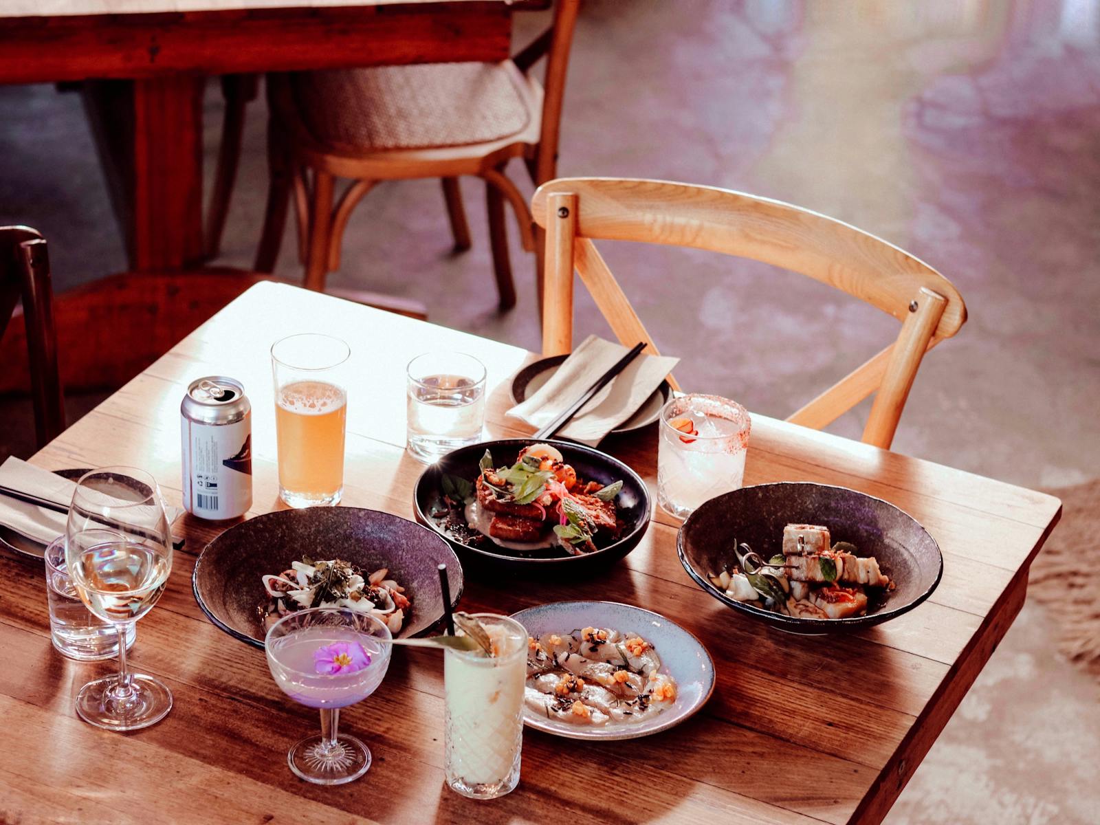 A tablescape features an array of savoury dishes,  cocktails, beer and water