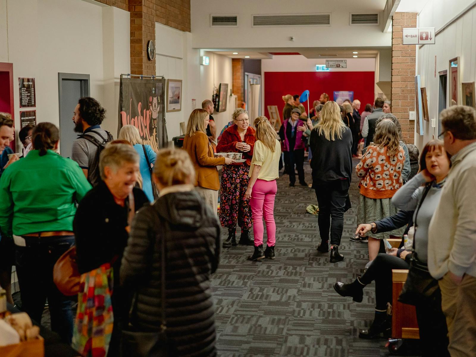 The foyer is being utilsed during an event - there are people spread out down a narrow hall