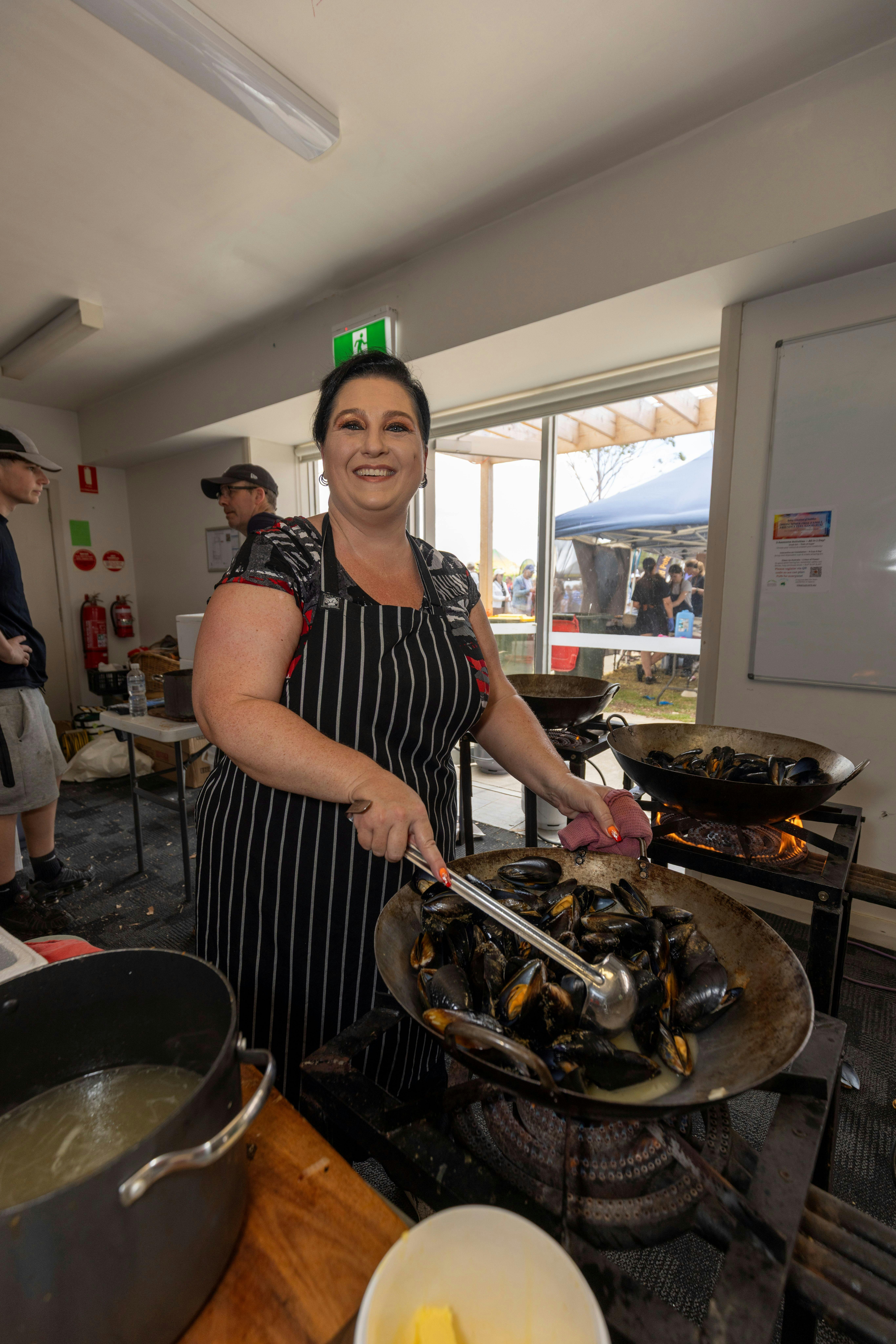 Person smiling at the camera and cooking mussels