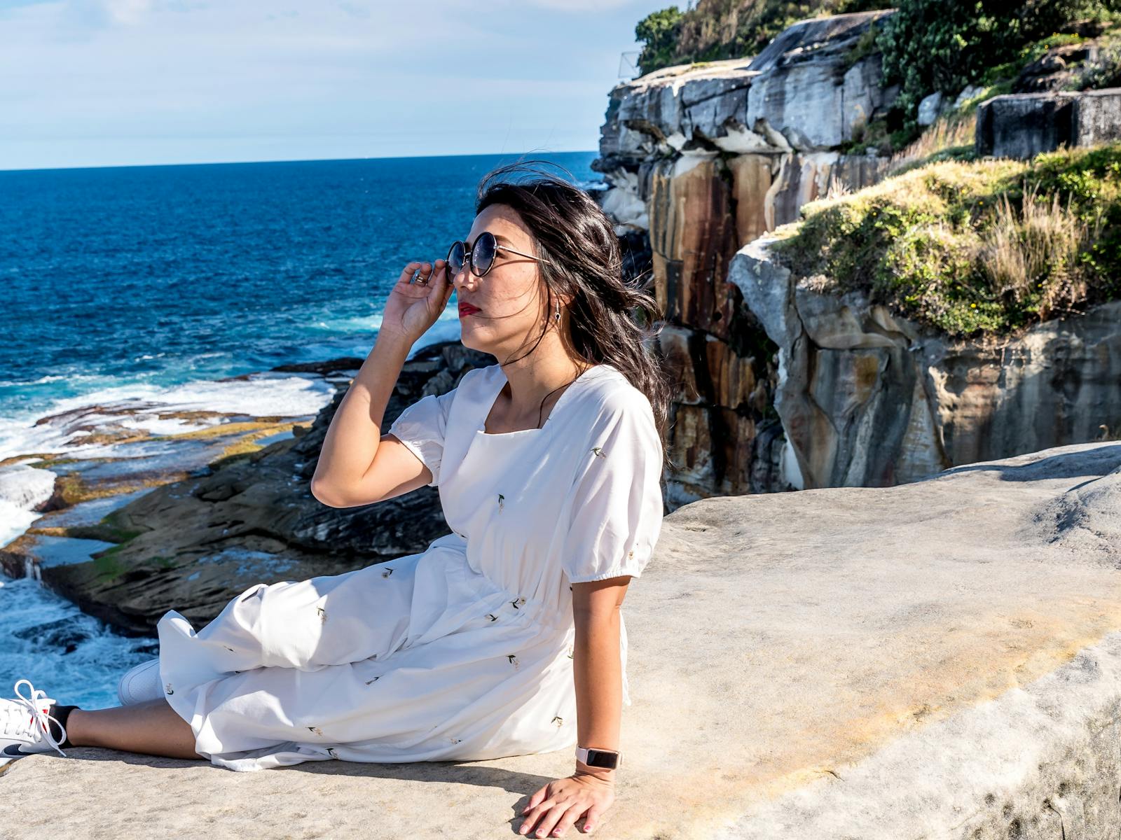 Young lady sits on a rock beside the ocean