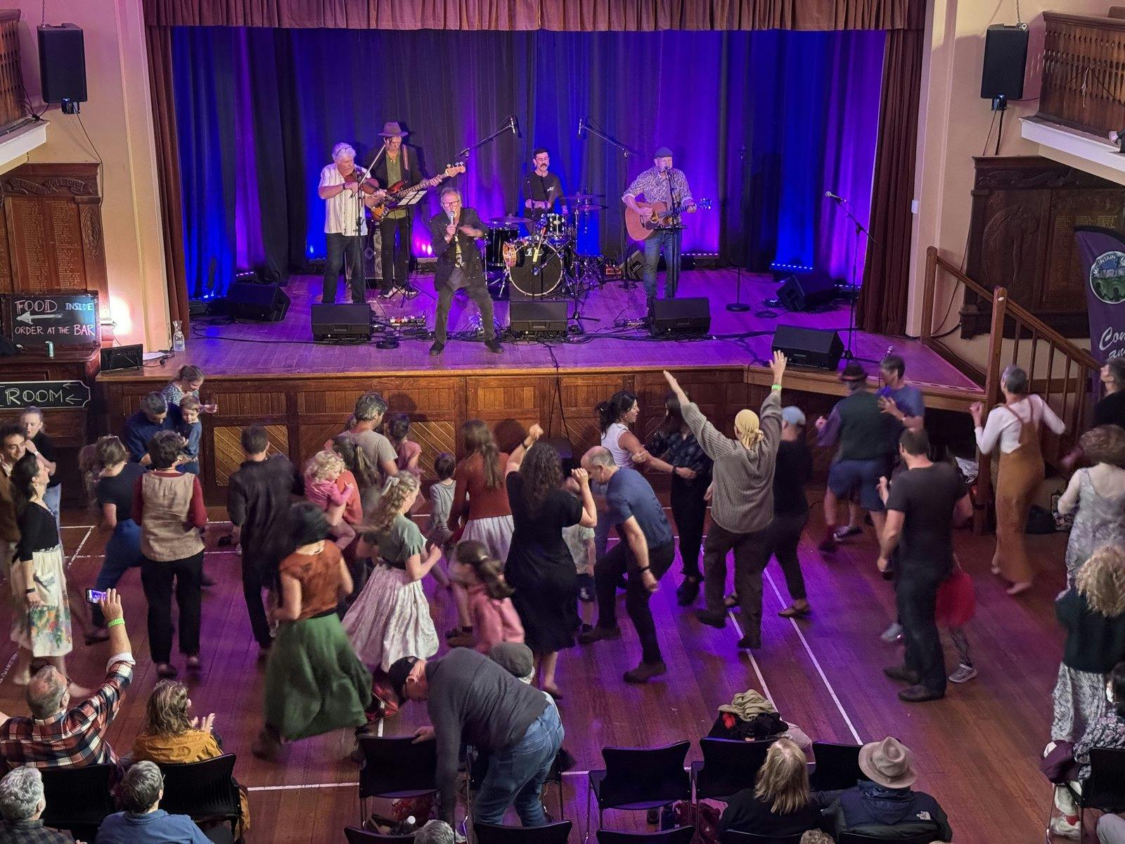 A crowd dancing to a live folk band on stage inside Sheffield Town Hall.