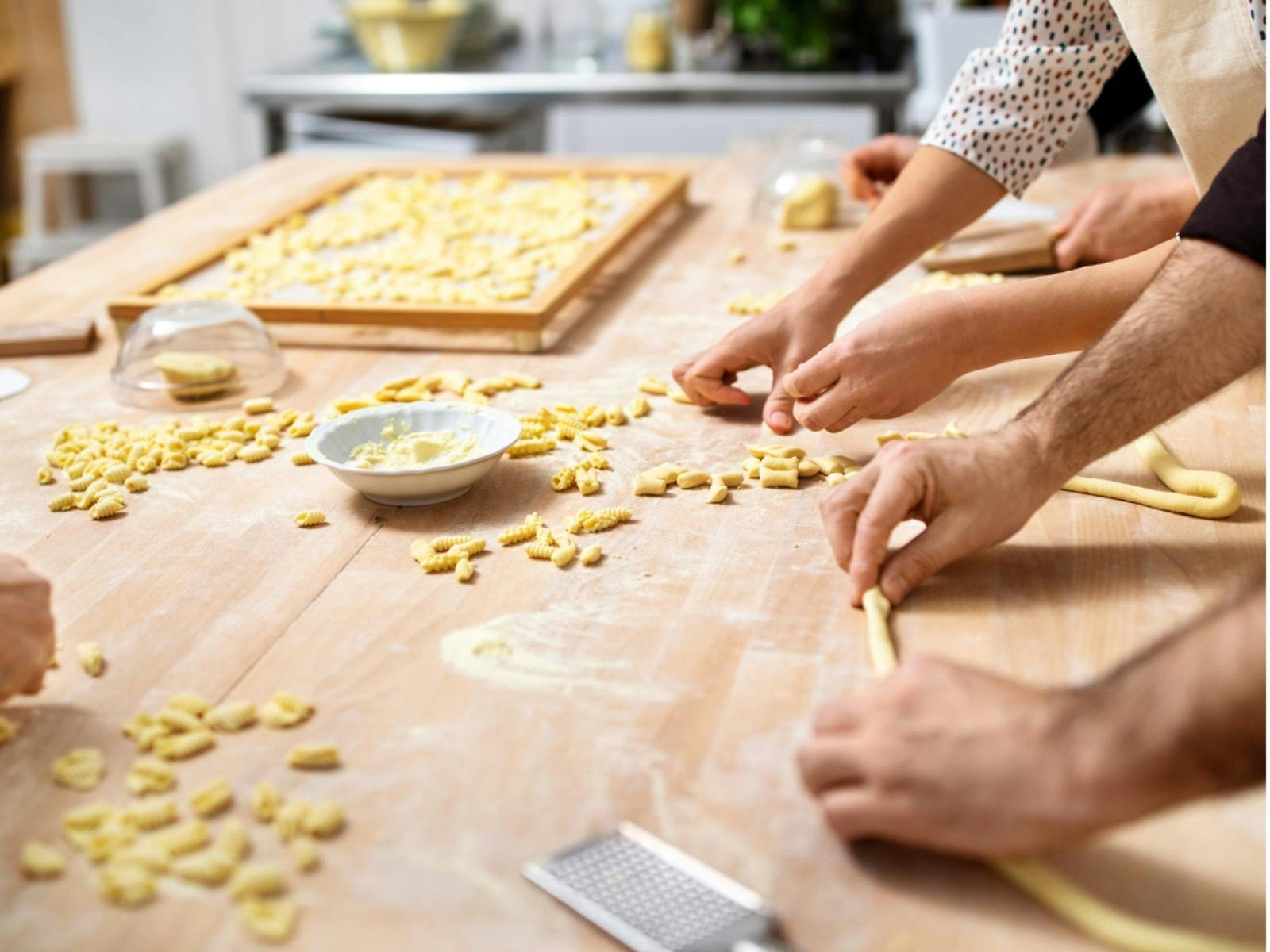 Two hands rolling cavatelli pasta on a board