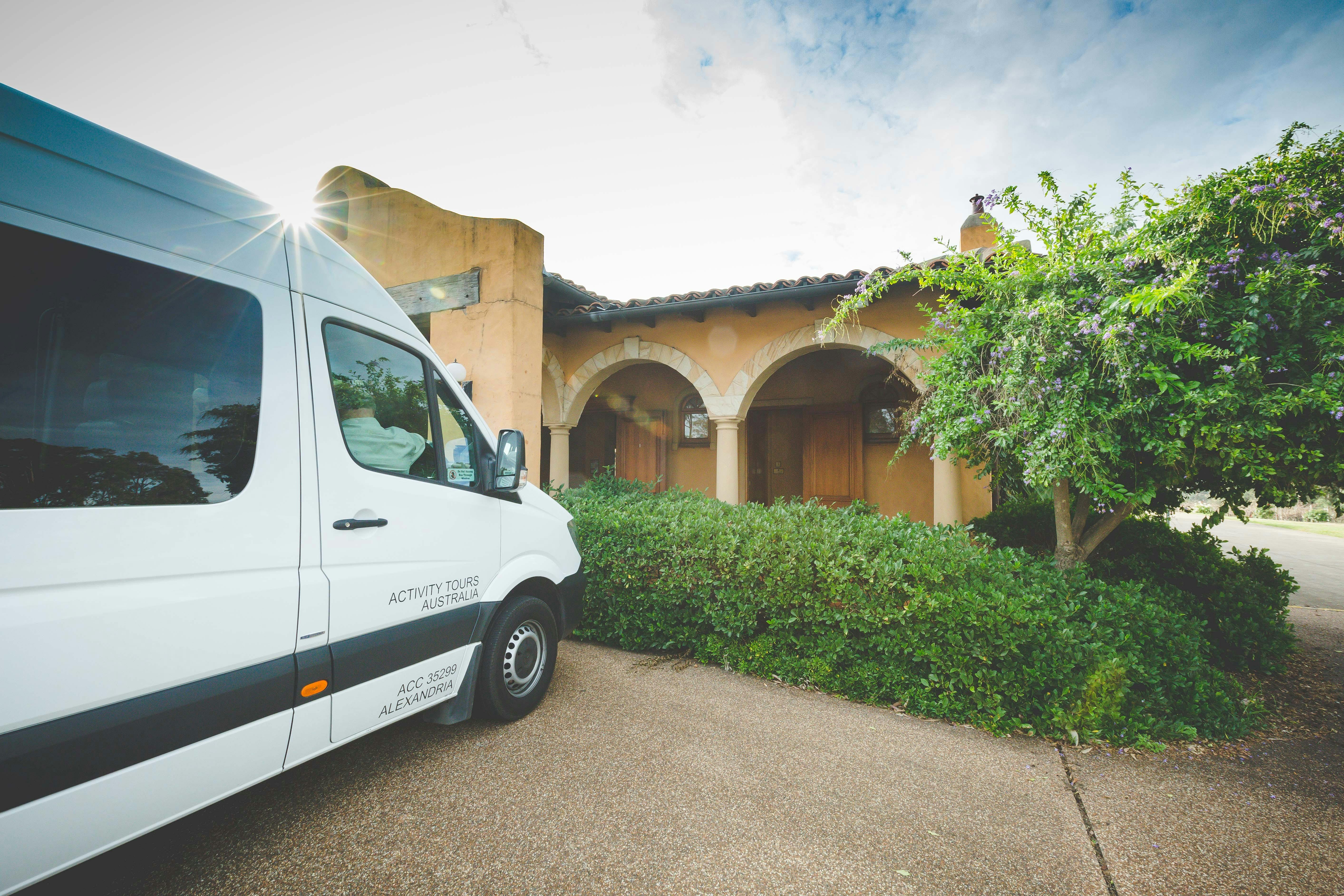 Weißer Tourbus parkt vor dem Weingutgebäude im mediterranen Stil mit gewölbtem Eingang