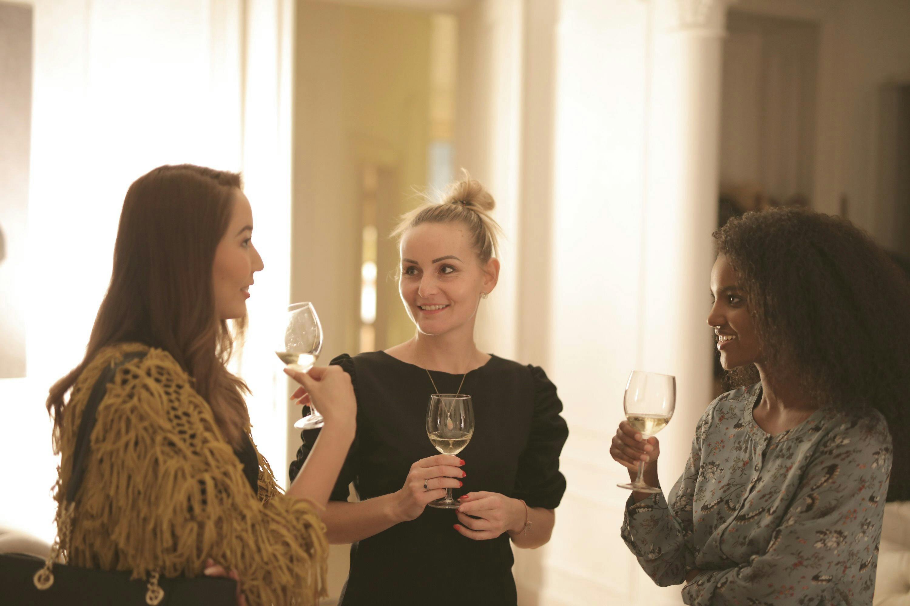 three people chatting with a glass of wine  in their hands