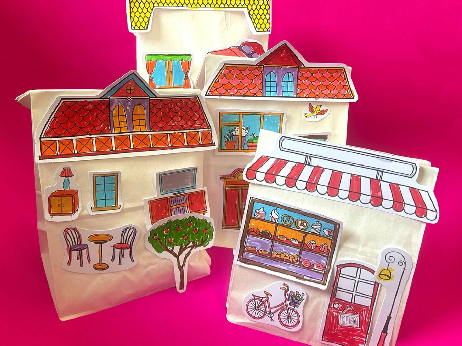 Pink backdrop with children's craft activity including stuffed paper bags with house parts attached