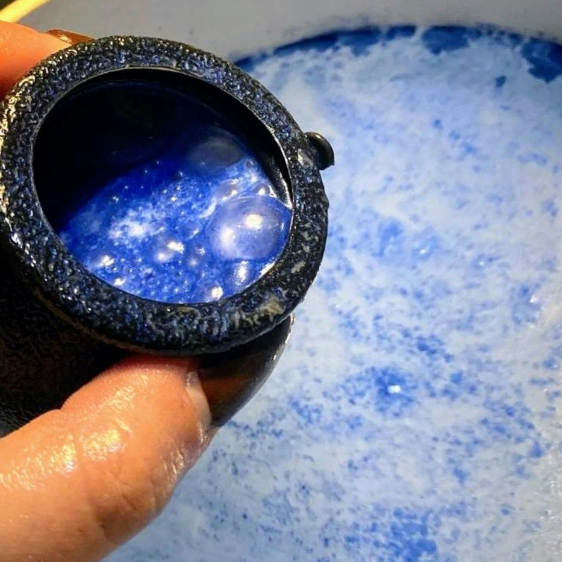 A bath bomb in cauldron, fizzing blue in the bath