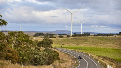 road with wind turbines in paddocks beside road