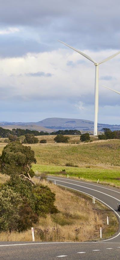 road with wind turbines in paddocks beside road