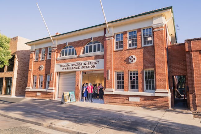 The exterior of the historic Wagga Wagga Ambulance Station. People are gathered at the door.