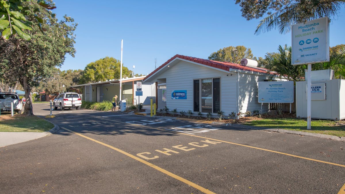 Shot of Mudjimba Beach Holiday Park entrance and check in lane with car and boom gate in shot