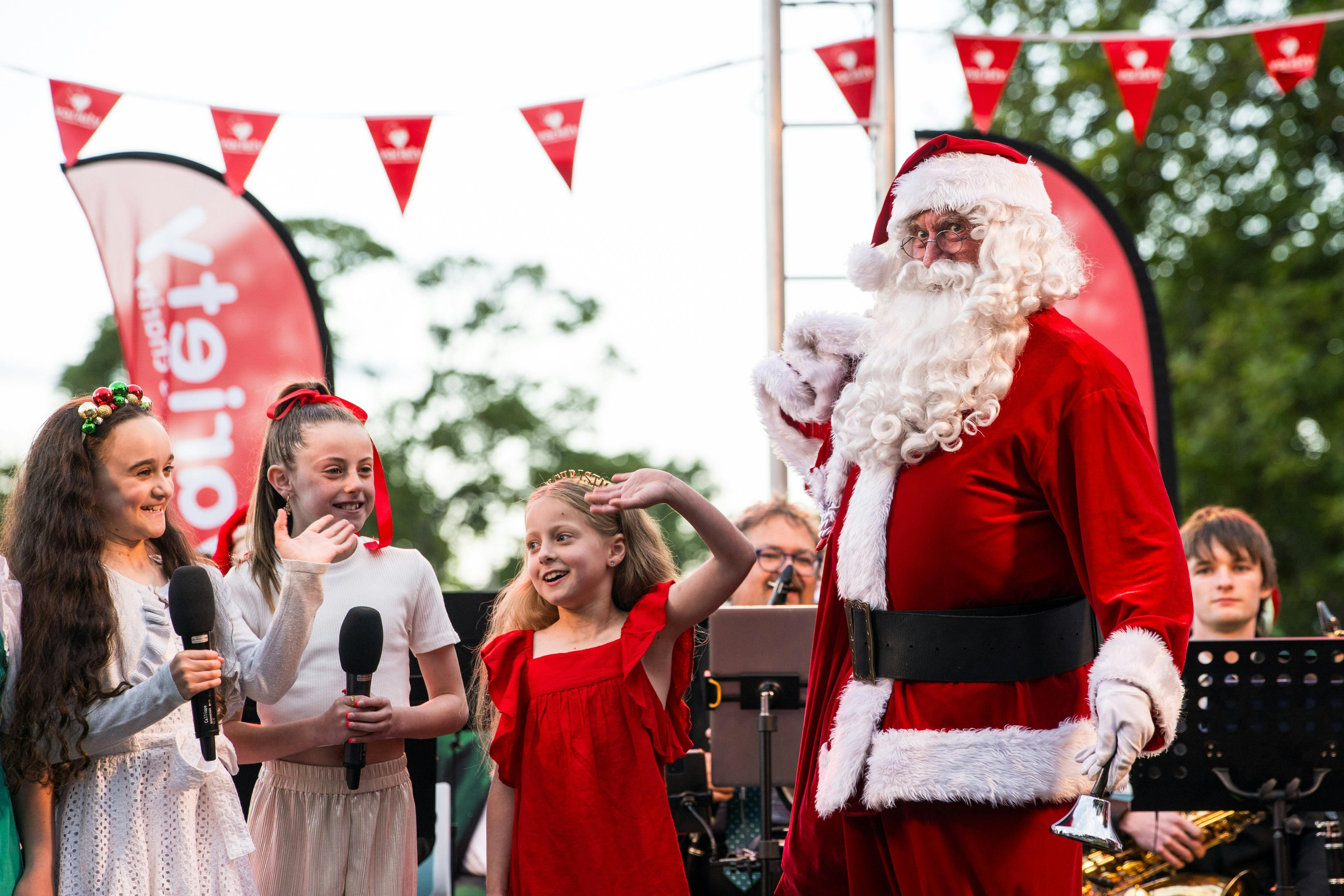 Santa on stage with kids at Variety Kids Carols