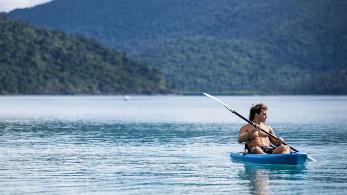Young guest enjoying kayak with mountains in background
