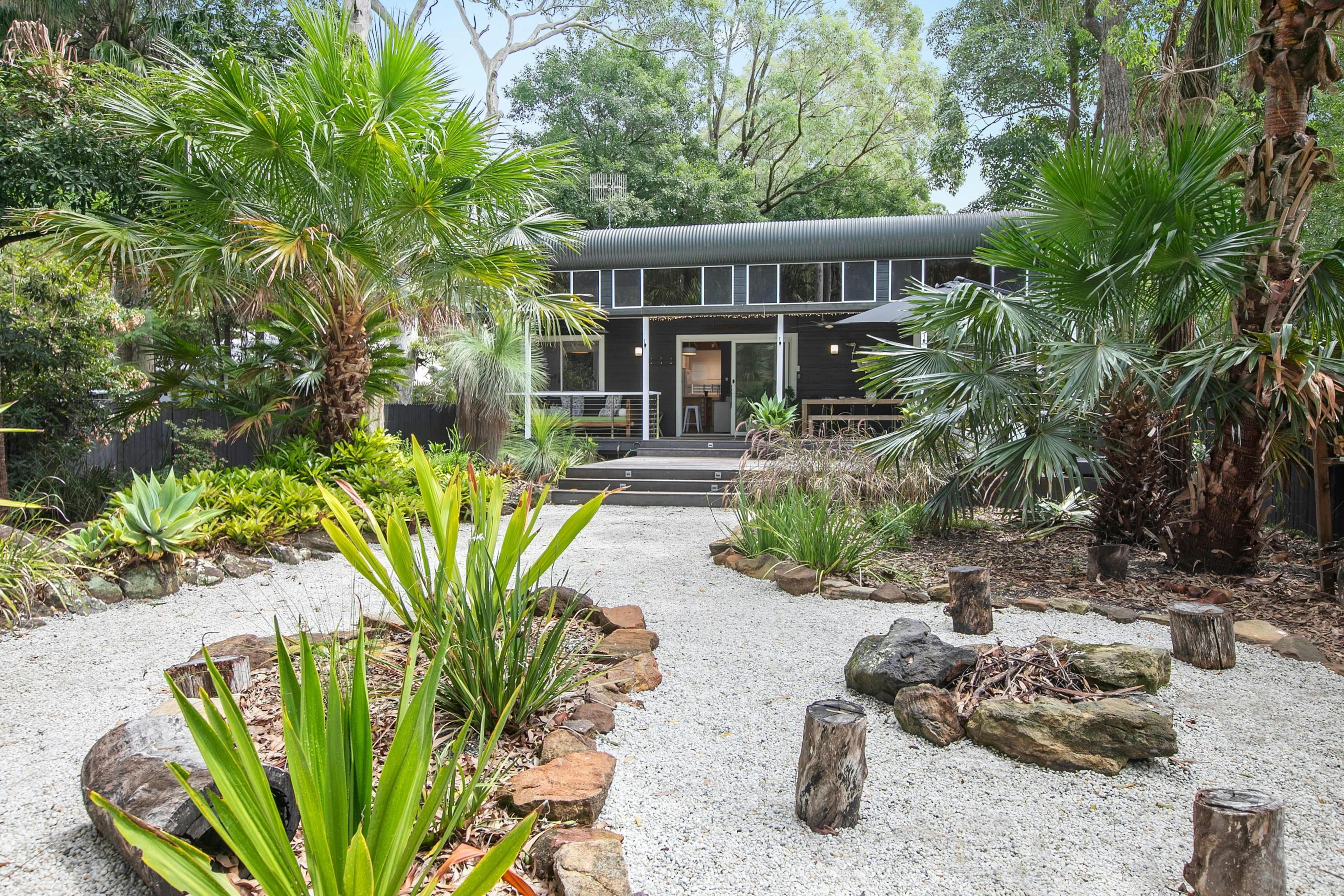 house facade , white gravel driveway and firepit area with seating